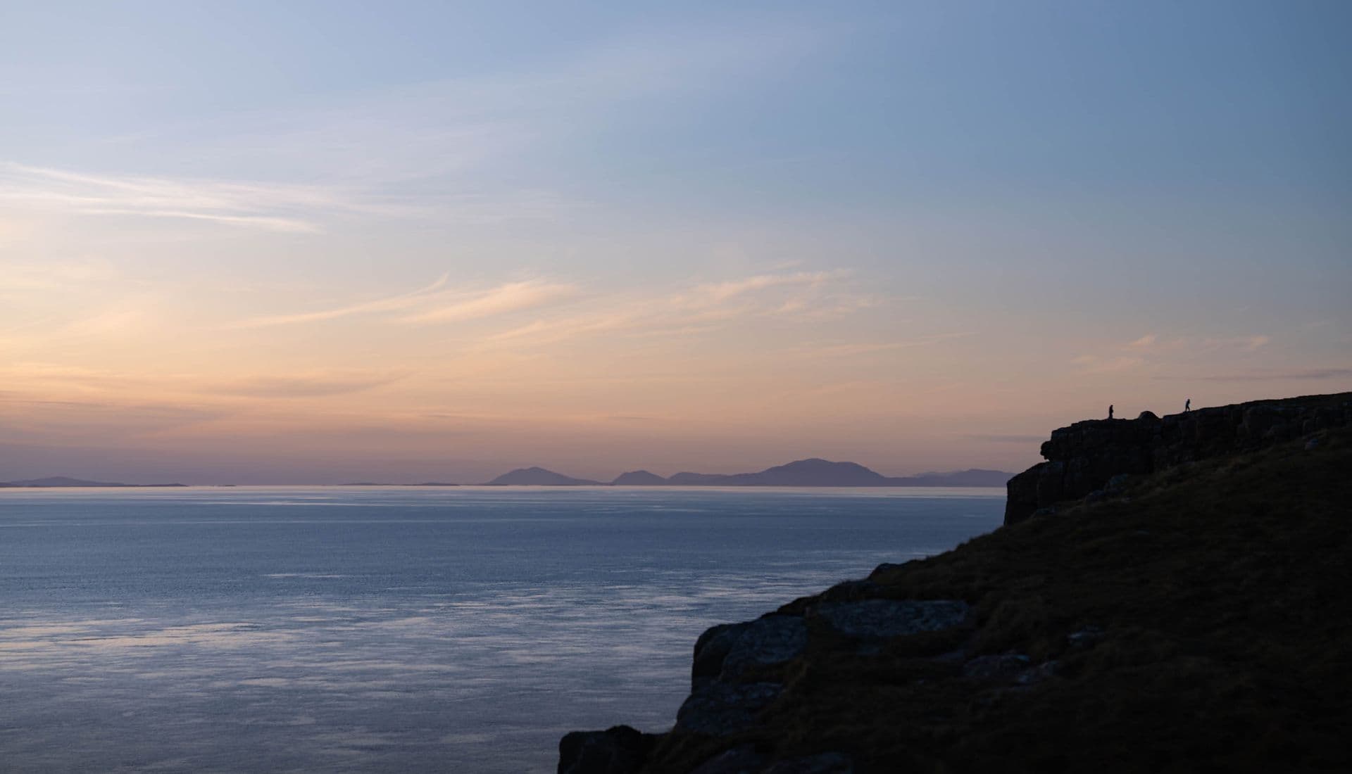 A sunset over the sea, with cliff silhouetted in the foreground - British elegance